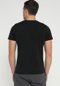 T-shirt in cotone nero con maniche corte, colletto tondo e una texture liscia. Vista posteriore che mostra un design pulito e accenti minimi.