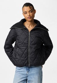 Kvaliteetne must õhkõrn jakk, millel on soonikkoes krae ja lukuga sulgu. Tekstureeritud kangas esitleb teemantmustreid. Kantud helesiniste teksadega.