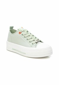 Zapatillas de lona verde claro con puntera y suela de goma blanca, diseño de cordones, con ojales naranjas y una entresuela texturizada.