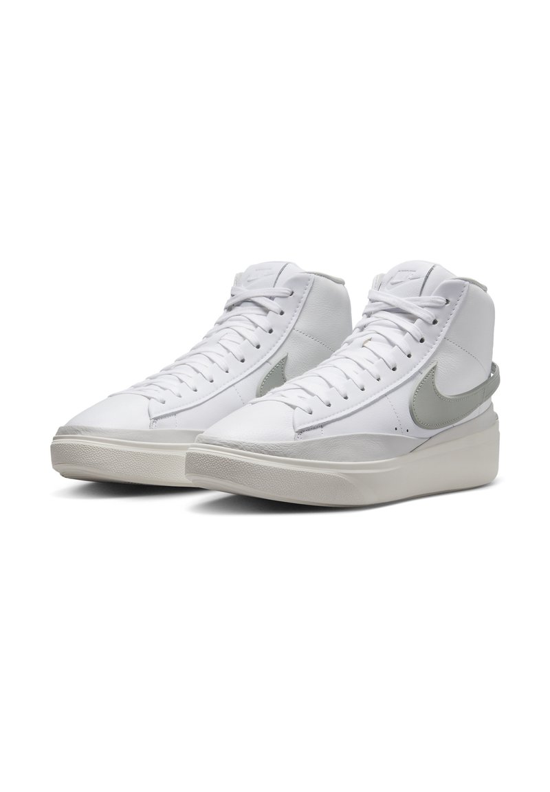 Sneaker alte bianche in pelle liscia, con punta rotonda, logo Nike grigio e suola in gomma testurizzata. Design con lacci.