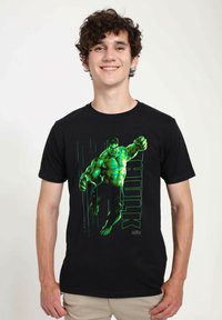 Černé bavlněné tričko s grafikou Hulka v akční póze v zelené a modré barvě, s textem "HULK" integrovaným do designu.
