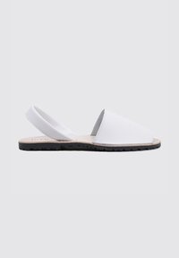 Sandalias blancas de tipo slip-on con puntera redondeada, material superior suave, correa ajustable en la parte posterior y suela de goma negra texturizada.