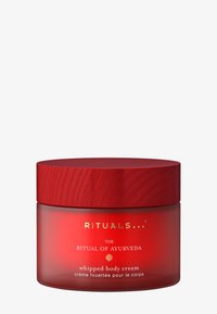 Punainen purkki, jossa on teksturoitu puukansi, kultakirjattu teksti "Ayurvedan rituaali" ja valkoinen etiketti, jossa lukee "vaahdotettu vartalovoide".