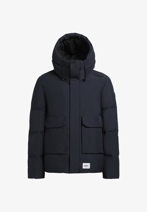 Mēteļa krāsas pūkains jaka ar augstu apkakli, lielām priekšējām kabatām un regulējamu kapuci. Uz priekšnola ir logotipa aplikācija. Tekstūras materiāls.