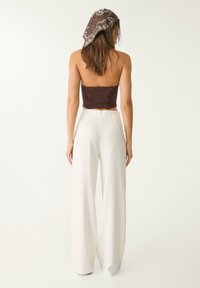 Brown smocked crop top paired with white wide-leg pants. The top features a textured design, and the pants have a smooth, flowing fabric.