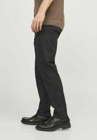 Pantaloni neri slim fit realizzati in misto cotone, con tasche laterali, una finitura liscia e abbinati a mocassini neri lucidi.