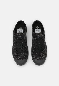 Zwarte sneakers met een stippenpatroon, stoffen bovenwerk, vetersluiting en rubberen zool, met een logo op de tong en een maatlabel aan de binnenkant.