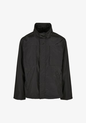 Mustapuku, joka on valmistettu kevyestä kankaasta, korkean kauluksen, kahden etutaskun ja rennon istuvuuden kanssa. Yksinkertainen muotoilu ilman näkyviä sulkijoita.