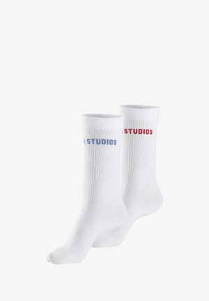 Coppia di calzini bianchi a coste, uno con la scritta "STUDIOS" in blu e l'altro con la scritta "STUDIOS" in rosso vicino alla parte superiore.