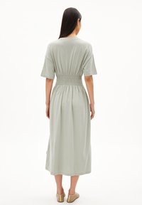 Light green, mid-length dress with a relaxed fit, short sleeves, and elastic smocked waistline, made from soft, smooth fabric.