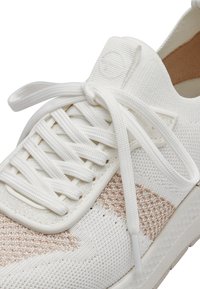 Valge sneaker tekstuursed pealmise osaga, millel on heledad pruunid kootud mustrid. Ümmargused lakknöörid ja diskreetne logo keelega lisavad detaili.