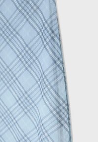 Tissu bleu clair avec un motif à carreaux croisés gris et blanc, drapé sur un fond uni clair.