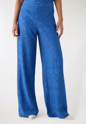 Pantaloni larghi blu in pizzo con dettagli intagliati e motivi a diamante intricati; vita elasticizzata e silhouette fluida.