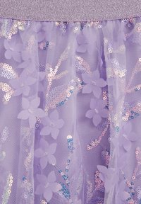 Svilena vijolična krilo iz tila, okrašeno s svetlečimi bleščicami in cvetličnimi aplikacijami; ima bleščeč srebrn pas, ki ustvarja večplastni teksturni učinek.