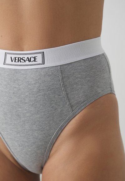 Boxers cinzentos com riscas, apresentando uma cintura elástica larga branca com o logótipo "VERSACE" em preto. Textura suave e design de corte alto.