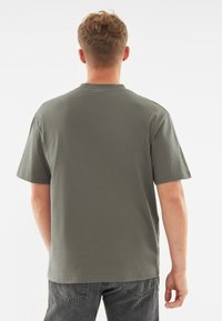 Korte mouwen shirt in olijfgroene katoen. Classic snit met een ronde hals, zichtbare stiksel en een gladde textuur. Geschikt voor casual kleding.