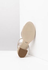 Sandalo beige con cinturini, finitura metallica liscia, caratterizzato da una suola in gomma testurizzata e tacco a piattaforma, etichettato con la taglia 37 e il logo del marchio.