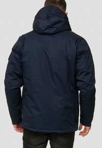 Mørk blå isolert jakke med hette, med en slank design, glatt tekstur og forsterkede sømmer.