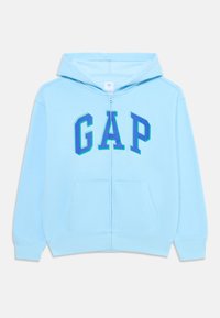 Lyseblå hettejakke med glidelås laget av myk stoff som har stor "GAP"-logo i mørkere nyanser av blått, med to frontlommer og hette med snøring.