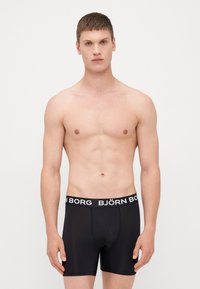 Μαύρο σλιπ με ελαστική ζώνη που φέρει την επιγραφή "BJÖRN BORG" σε λευκό χρώμα. Λείο, εφαρμοστό σχέδιο, φτιαγμένο από ελαστικό υλικό.