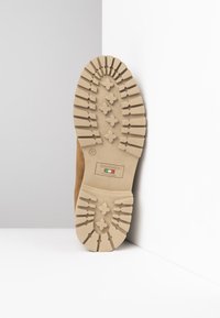 Scarpa in suede color tan con suola in gomma beige caratterizzata da una presa con motivo e logo del marchio, contrassegnata dalla taglia 37. Prodotta in Italia.