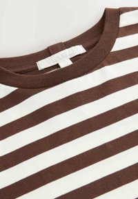 Ruskea ja valkoinen raidallinen t-paita, jossa on pyöreä pääntie. Pehmeä puuvillakangas, jonka pinta on sileä. Tunnus näkyvissä kauluksessa.