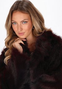 Burgundy faux fur shawl with a soft texture, featuring a loose fit and subtle sheen. Accented by a high collar and flowing edges.