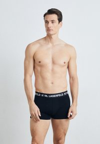 Crne pamberske bokserice s širokim elastičnim pojasom na kojem je u bijeloj boji logotip "Karl Lagerfeld". Prilagođen dizajn s glatkom teksturom.