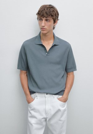 Grå pikétröja med korta ärmar, texturerad ribbad design, treknapparsknäppning och avslappnad passform, matchad med vita byxor.