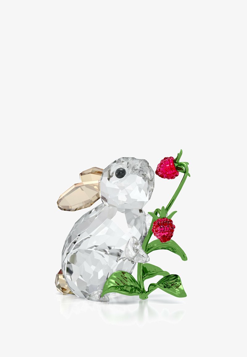 Figurita de conejo de cristal claro con orejas beige, sosteniendo un tallo verde con dos acentos de frambuesa roja, detallada con facetas para darle textura.