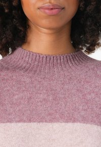 Strickpullover mit hohem gerippten Kragen, der ein Verlaufsmuster in hellrosa und sanftem Mauve zeigt. Weiche, strukturierte Wollmischung.