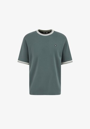 Īsā piedurkne zaļa T-krekls ar baltu un melnu svītrainu apmali apkaklē un piedurknēs, ar mazu izšūtu putna logotipu uz krūtīm.