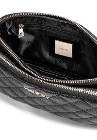 Črna usnjena torba z vzorcem rahlega šivanja. Ima zlat zadrgo, gladko notranjo oblogo in oznako blagovne znamke na notranji strani.