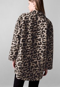 Leopardiain kuosi beige- ja mustana, valmistettu teksturoidusta kankaasta, jossa on väljä malli, leveät hihat ja kaulus.