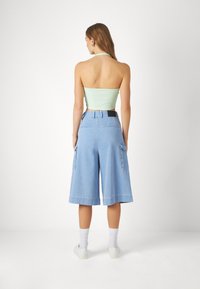 Light green ribbed halter top paired with loose-fitting light blue denim culottes featuring side pockets and a straight cut at the hem.