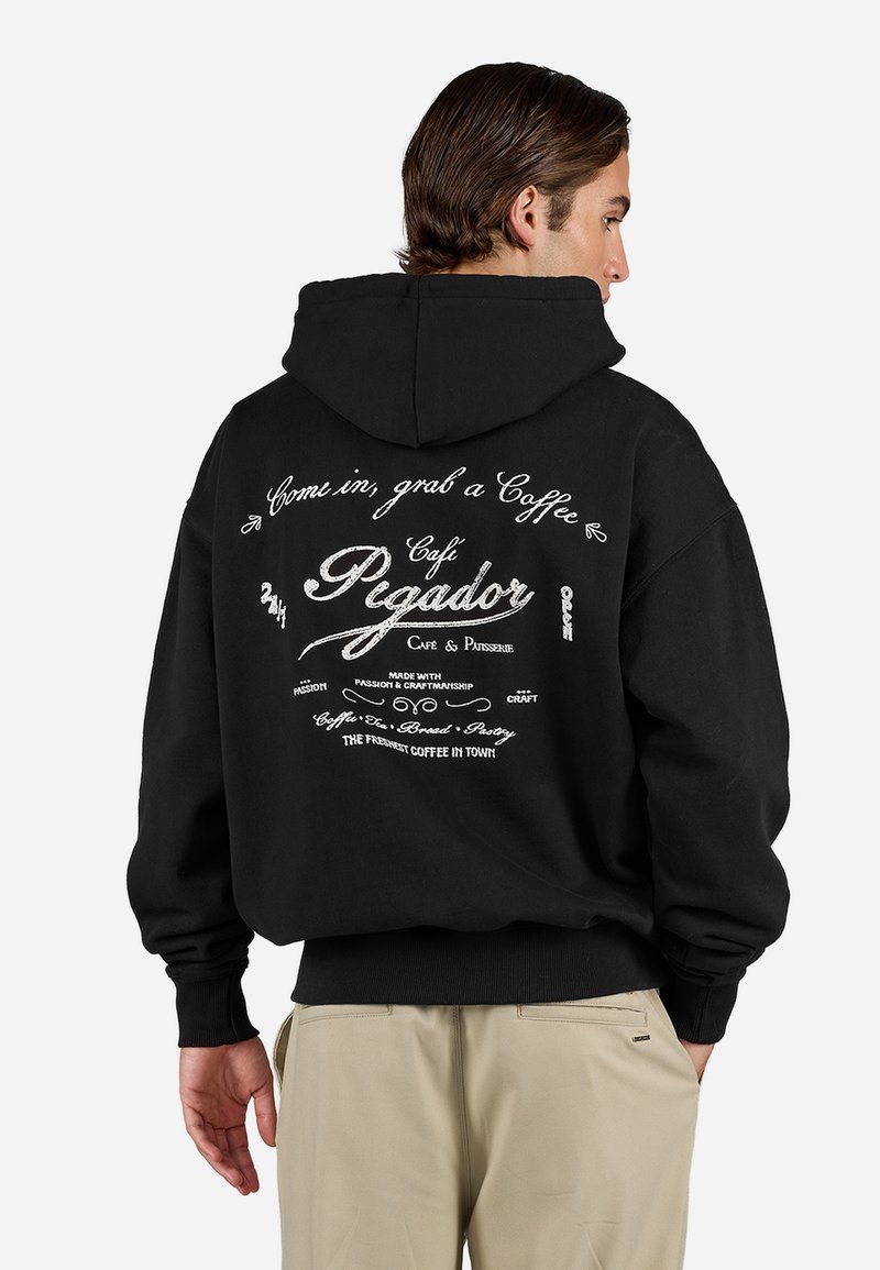Black hoodie with a large white graphic on the back featuring text about a café. Soft fabric, loose fit, ribbed cuffs and hem.