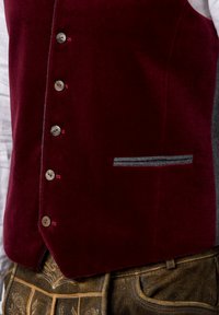 Bordeaux samtene Weste mit silbernen Knöpfen, einer grauen Filztasche und taillierter Passform, kombiniert mit braunen gemusterten Hosen.