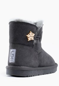 Botín de ante gris con un interior esponjoso, que presenta un acento decorativo de copo de nieve de madera y una suela de goma. Etiqueta de la marca en el lateral.
