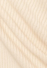 Cream-colored knit fabric with a textured, ribbed pattern, showing soft fibers and slight shine, arranged in overlapping folds.