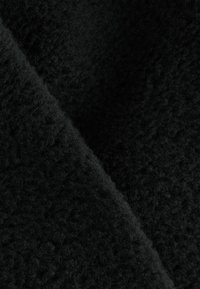 Svart texturerad tyg med en mjuk, lurvig yta som visar en något marmorerad framtoning och subtila variationer i djup.