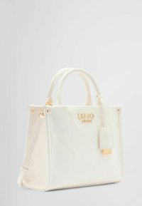 Sac à main blanc avec motif matelassé, quincaillerie dorée, doubles anses supérieures et une bandoulière amovible. Présente un logo de marque à l'avant.