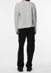 Maglione grigio chiaro a coste con vestibilità comoda abbinato a pantaloni cargo neri con tasche laterali e design a gamba dritta.