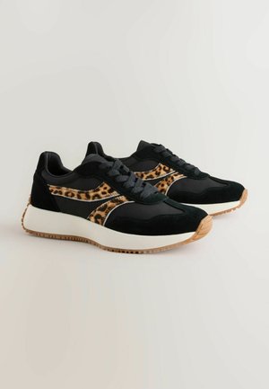 Melni sporta apavi ar leoparda raksta akcentiem, no zamšādas un tekstila materiāliem, ar šņorītēm, baltu mīkstinātu viduszoli un gumijas zoli.