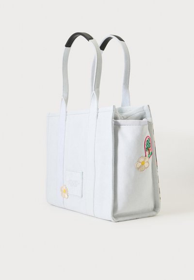 Sac fourre-tout en toile bleu clair avec poignées noires et fleurs brodées blanches et jaunes sur les panneaux avant et latéraux.