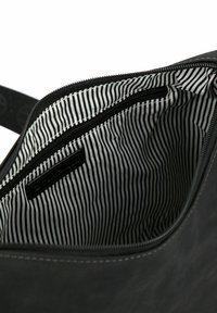 Interno di una borsa in tessuto nero con un motivo a righe. Presenta una cerniera e una tasca con cerniera aggiuntiva. Texture liscia e forma strutturata.
