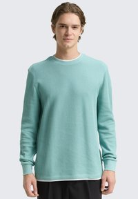 Helles türkisfarbiges, geripptes Langarmshirt mit Rundhalsausschnitt und lockerer Passform. Verfügt über Umschlagärmel und einen schichtartigen Look am Saum.