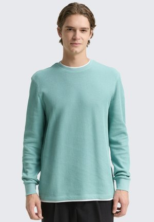 Helles türkisfarbiges, geripptes Langarmshirt mit Rundhalsausschnitt und lockerer Passform. Verfügt über Umschlagärmel und einen schichtartigen Look am Saum.