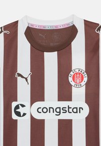 Brązowa i biała pionowo prążkowana koszulka piłkarska wykonana z oddychającej tkaniny, z okrągłym dekoltem, logo Puma oraz emblematem FC St. Pauli.