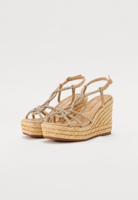 Brune kile sandaler med flettet jute hæl, metalldetaljer på stroppene, og åpen tå-design. Myk fotseng og justerbar ankelstropp er inkludert.