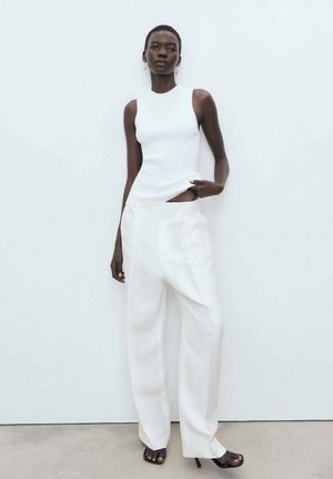 White sleeveless top and wide-leg white trousers. Smooth, ribbed texture on the top, with a relaxed fit and side cutout detailing.